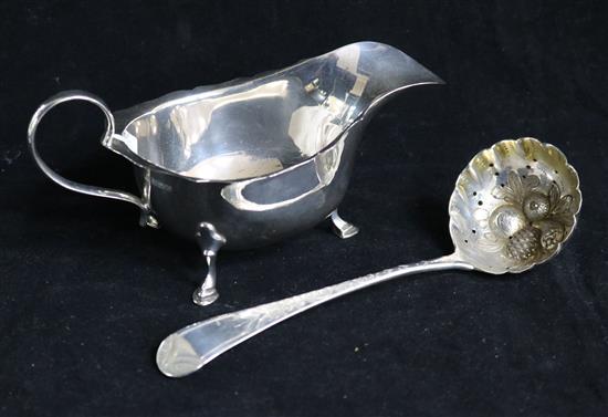 A silver sauceboat and a silver spoon.